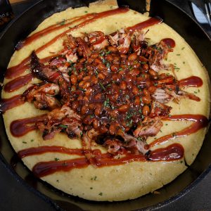 Cornbread mit Pulled Pork und BBQ Beans in der Mitte, garniert mit BBQ Sauce