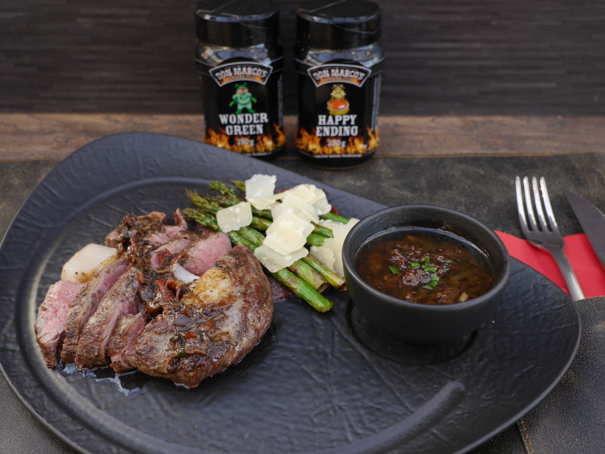 surfnturf (0) Surf n' Turf Steak auf schwarzem Teller mit Rub Dosen im Hintergrund