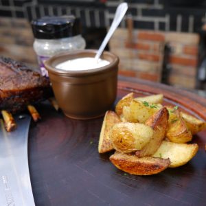 Rotisserie Ribs 3 Dip neben Kartoffelecken auf Holzplatte