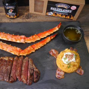 Süßkartoffelpüree, Crap legs und Steak auf Schiefplatte mit Salzplanke und Gewürz im Hintergrund
