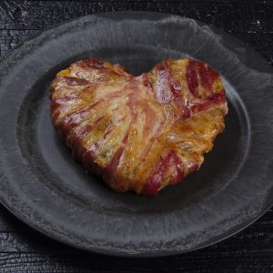 baconherz mit beilage auf schwarzem teller