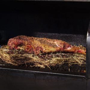 lammkeule im Smoker auf einem Bett aus Heu und Kaffeebohnen Nahaufnahme
